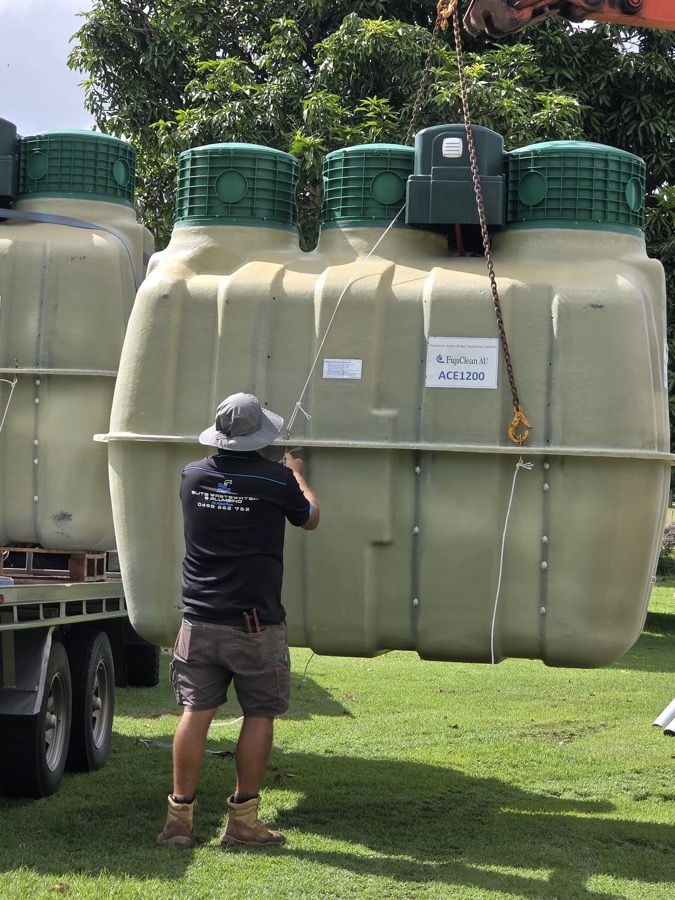 A worker beside wastewater treatment tanks loaded on a truck