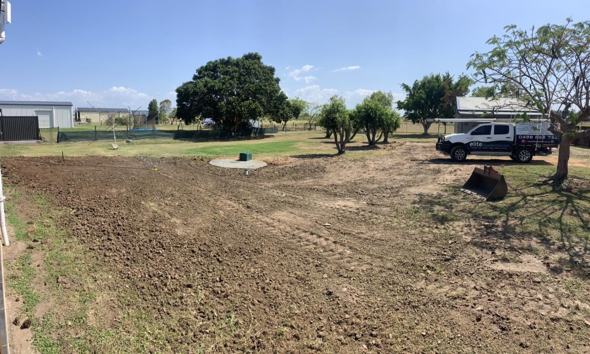 A levelled rural block with a ute parked beyond the cleared ground after a system install