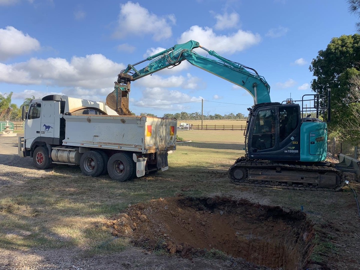 An excavator loading soil into a tipper truck on a work site