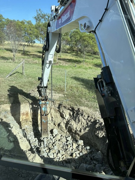 A trench being dug, seen from inside the excavator cab