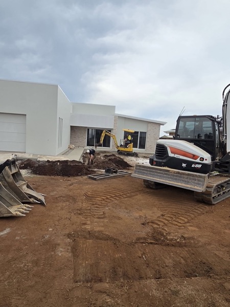 An excavator working in front of a newly built commercial building