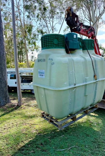 A treatment tank strapped down on a trailer beside a ute