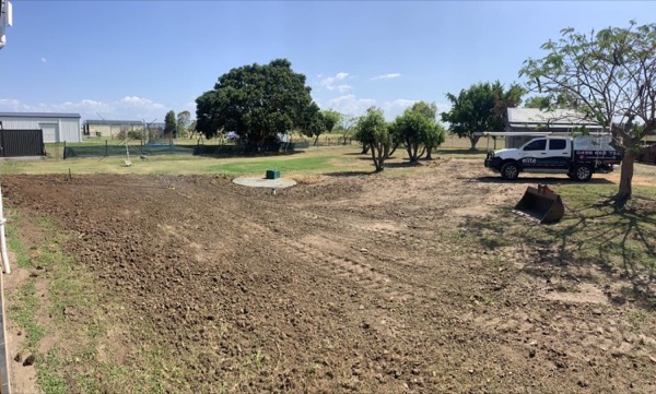 A levelled rural block with a ute parked beyond the cleared ground