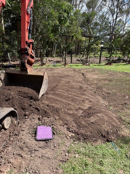 An excavator bucket beside a mound of excavated soil