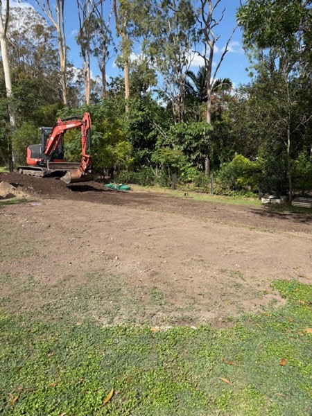 An excavator working on a grassed suburban block